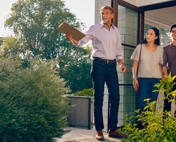agent standing at front door of house with couple behind them