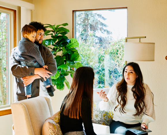a family of two adults and child talking with agent in room