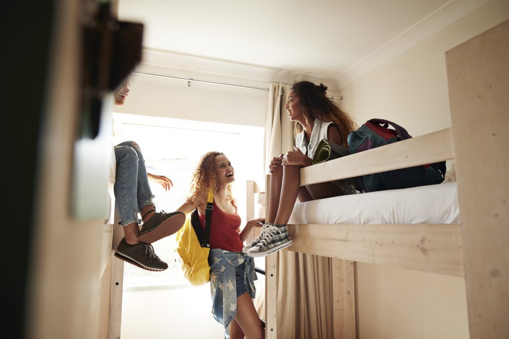Young women arriving to room with bunk beds, at college dorm