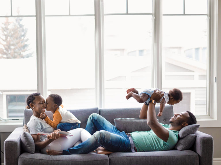 Affectionate young family interacting with each other on living room sofa.