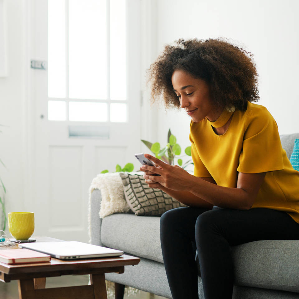 woman sitting on couch with smartphone in her hands