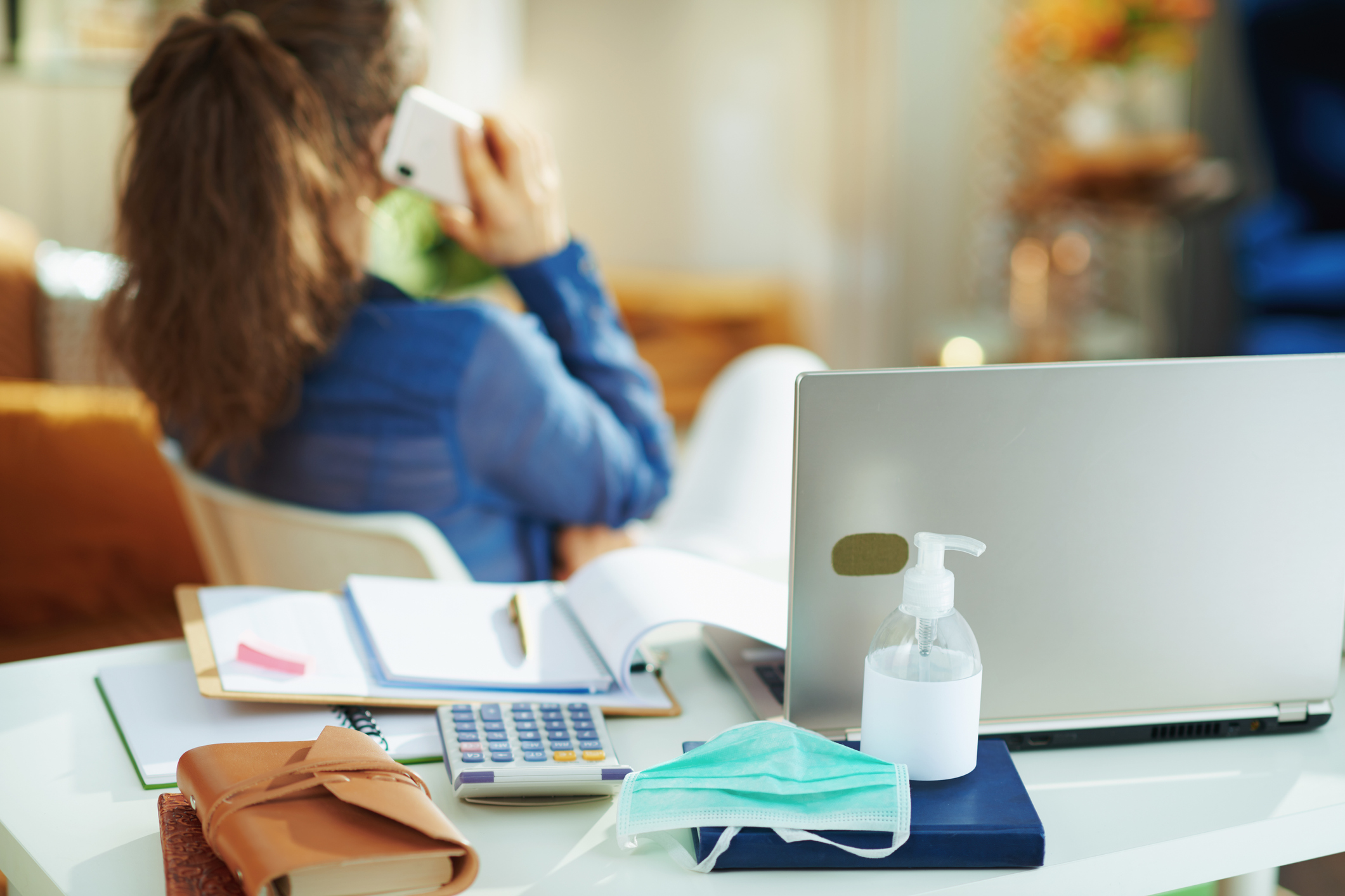 work-from-home desk setup with person in the background talking on phone