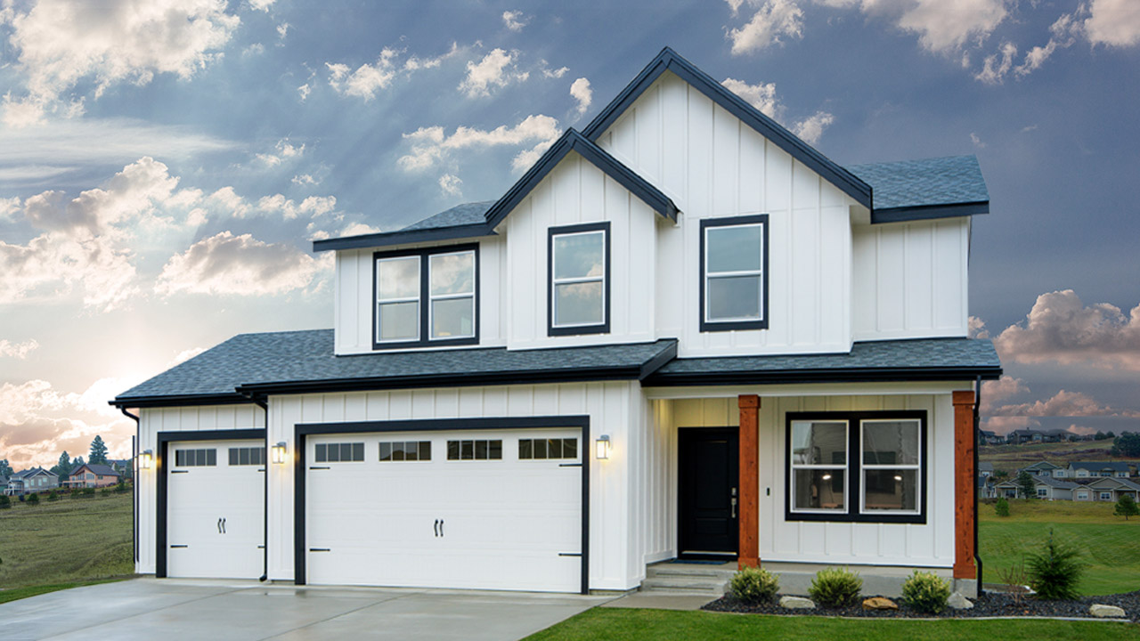 White 2-story house with 3 car garage surrounded by grass