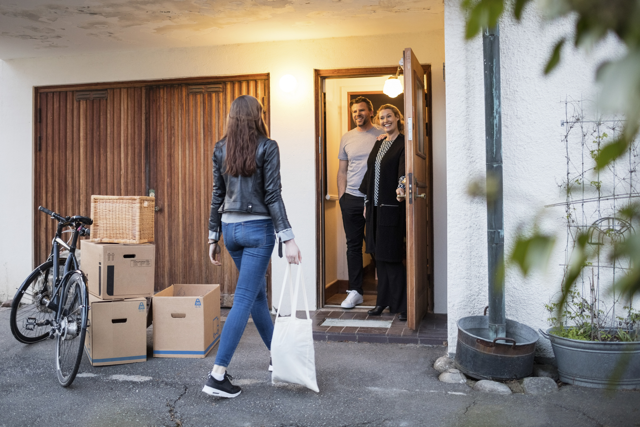 young woman is greeted at the front door of a home by her parents