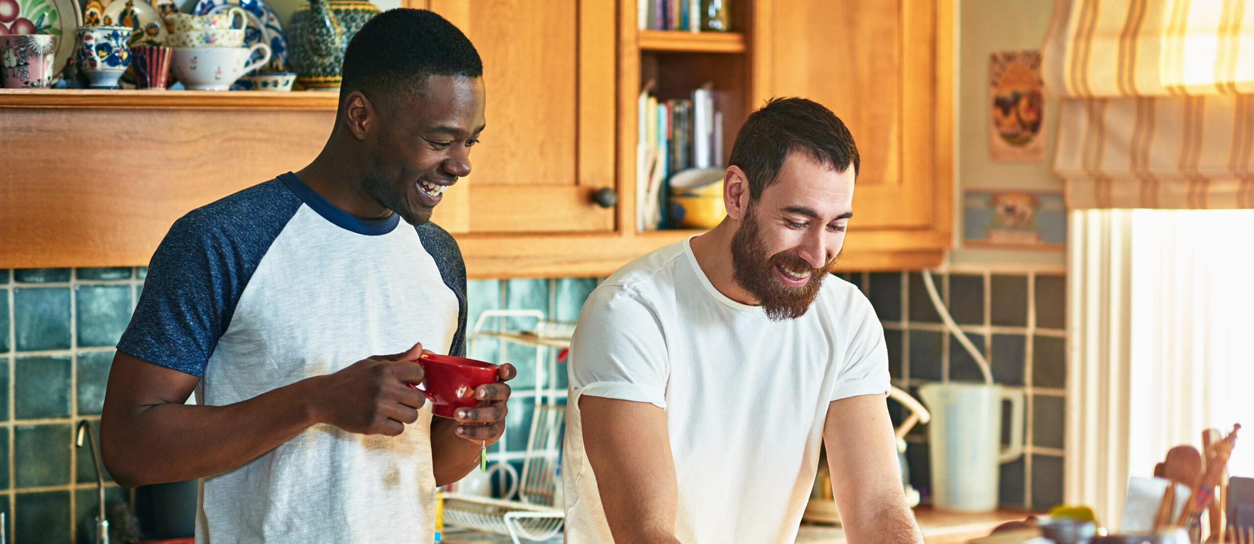 Two male roommates laughing in apartment kitchen how to find roommates in NYC