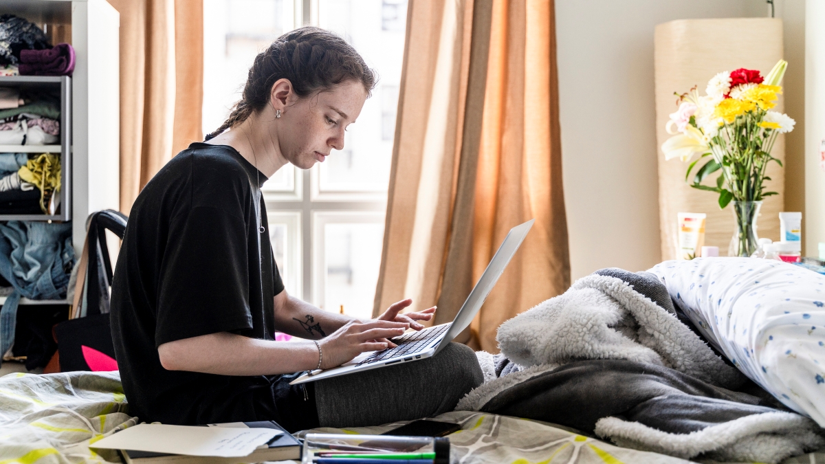 Person sitting on a bed using a laptop