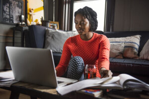 Woman using laptop at home looking up how to sublet your apartment in NYC