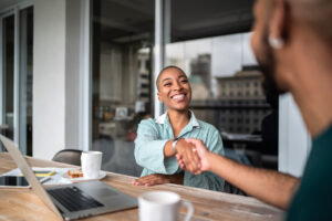 smiling woman shaking hands with someone after real estate negotiation