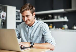 man learning real estate terms on laptop and smiling