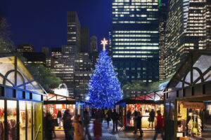 lit-up tree behind stalls at Bryant Park Winter Village holiday markets nyc