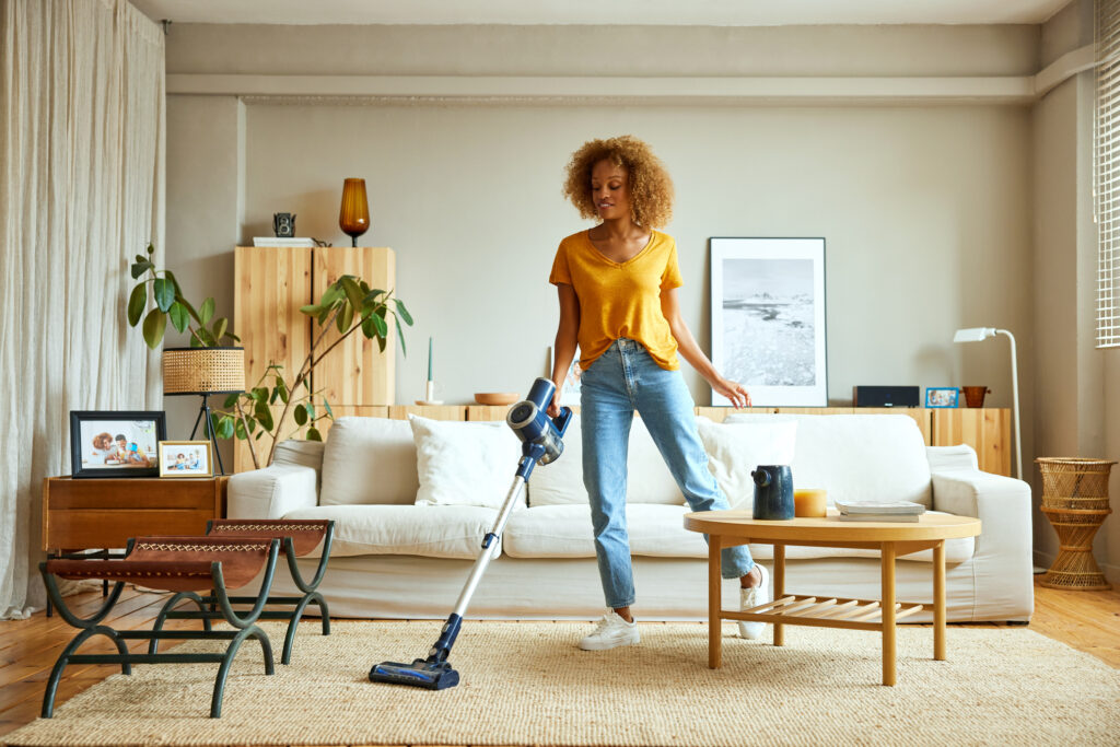woman vacuuming carpet - prepare nyc apartment before traveling