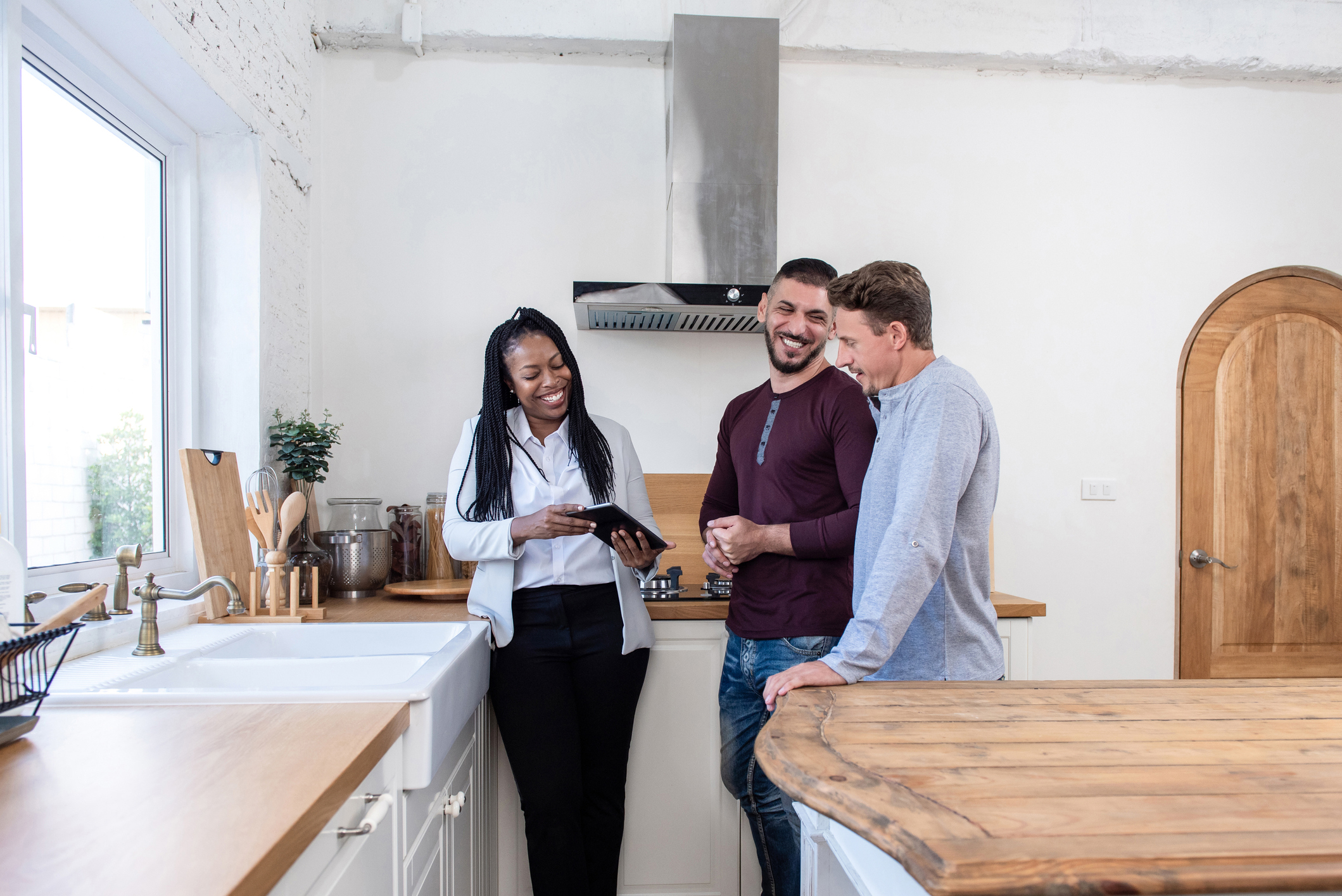 two men laugh with real estate agent while attending an open house