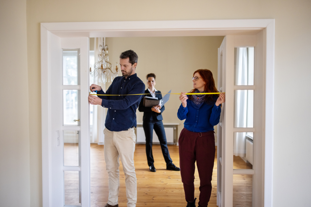 couple measuring doorway as agent looks on - open house tips for renters