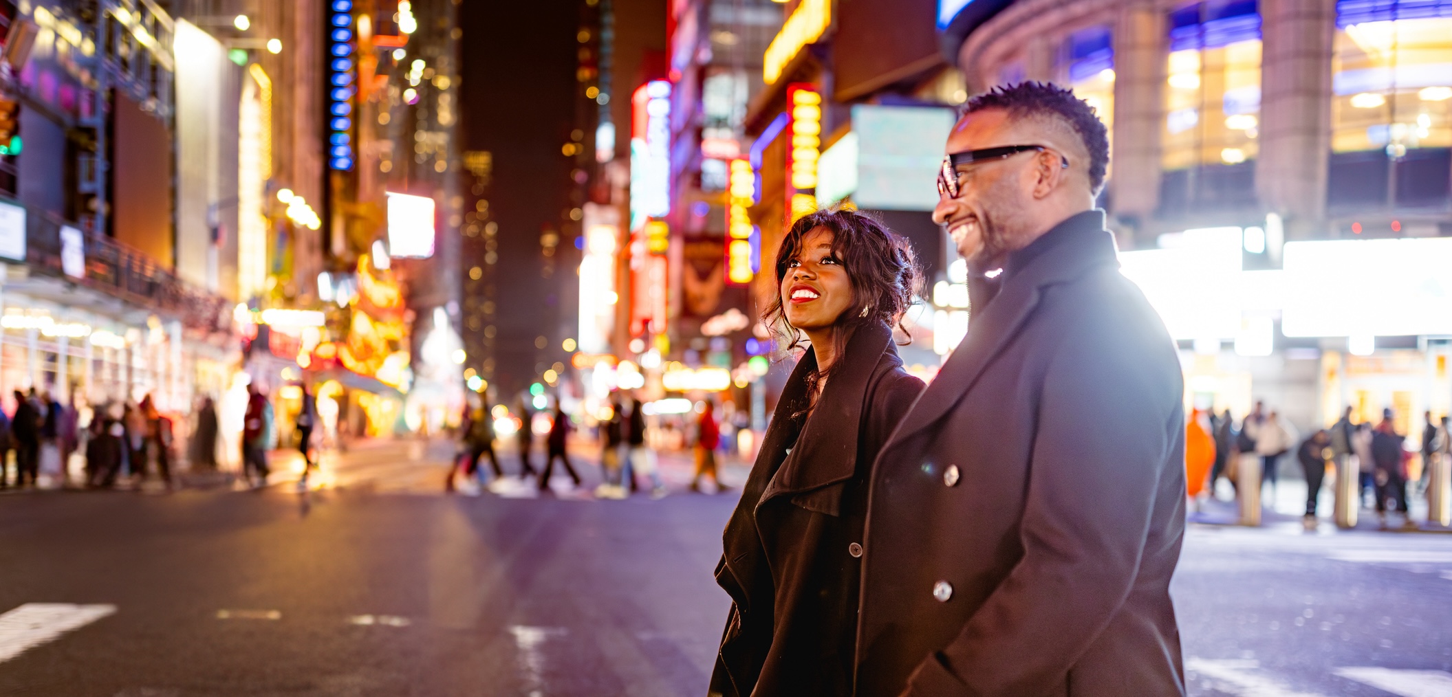 Man and woman walk through Times Square at night - live in Times Square