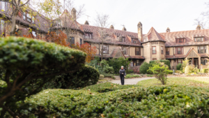 woman walks in garden behind tudor-style homes in Forest Hills, Queens