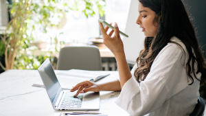 Woman using phone and laptop