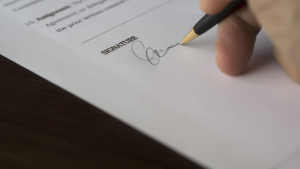 Close-up of hand signing document