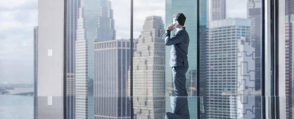 Businessman on the phone in New York City office looking out window