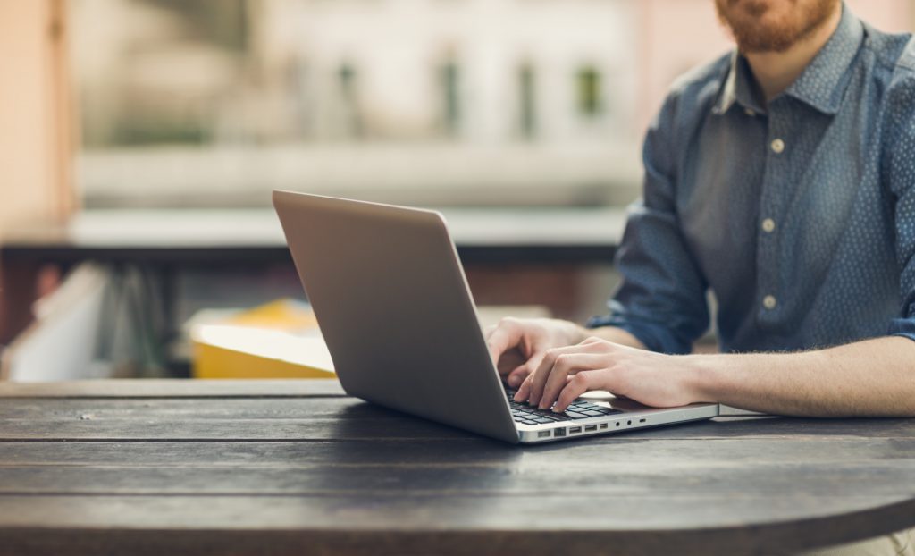 A landlord using his laptop to calculate raising rent on a tenant.
