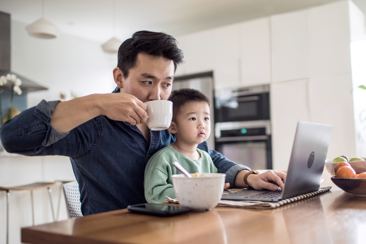 An interested home buyer researching what documentation is needed for a mortgage with his son sitting on his lap.