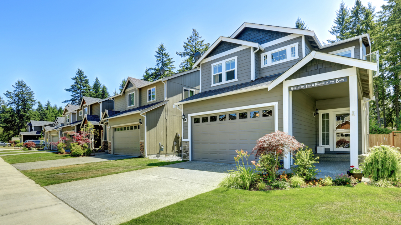 Block of single family house exteriors with a front porch, driveway, and landscaped yard.
