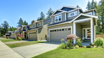 Block of single family house exteriors with a front porch, driveway, and landscaped yard.