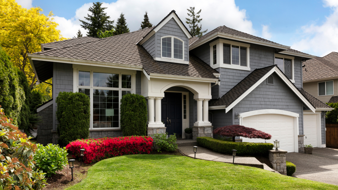 Home exterior with blooming flowers and trees with lush green grass front yard