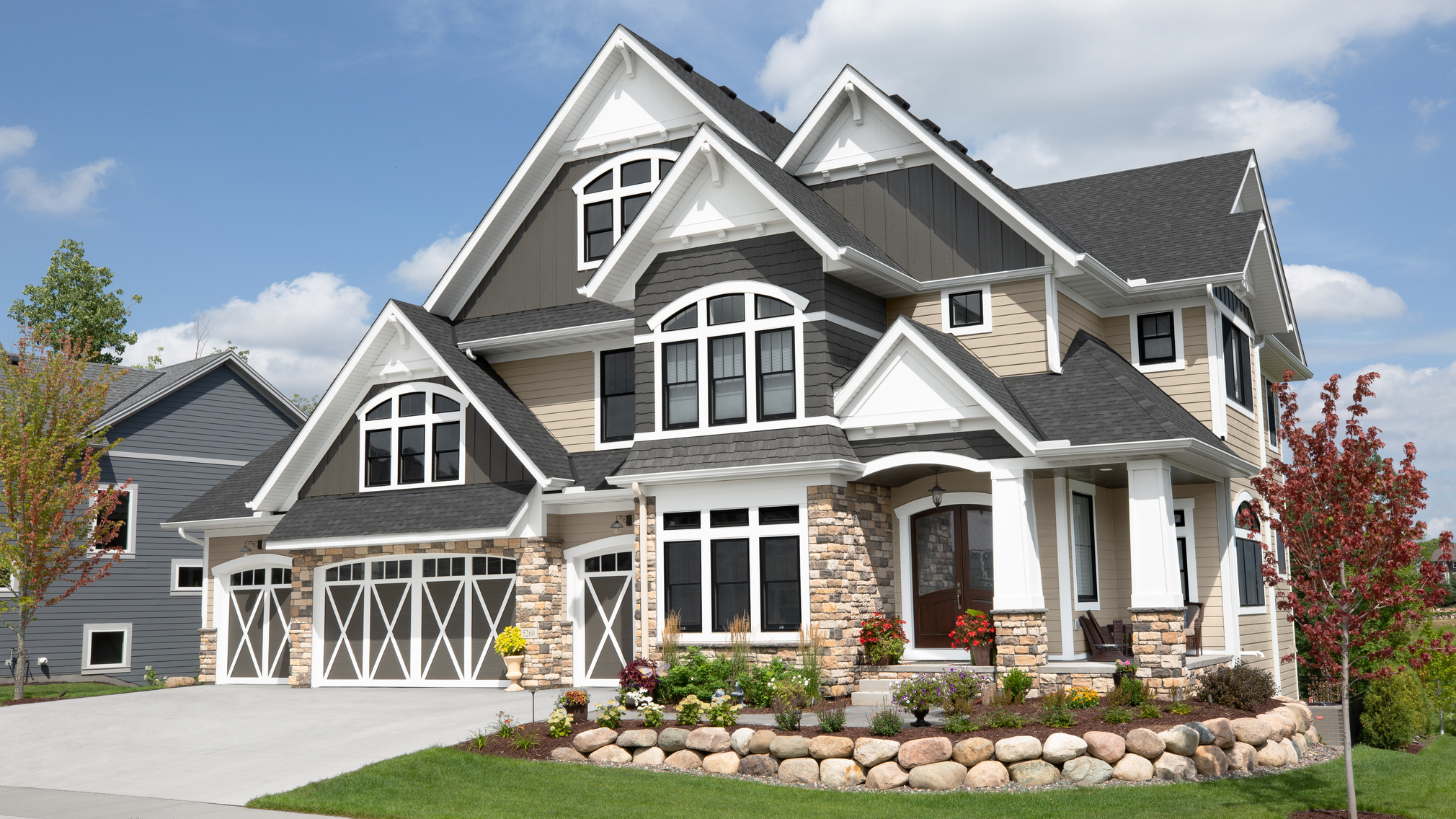 gray, white, and tan single family home exterior with manicured lawn.