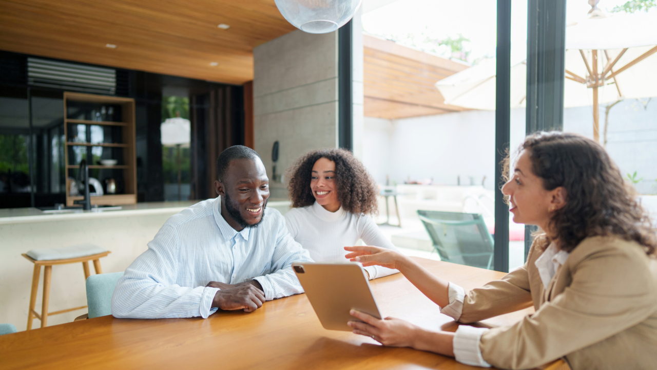 A professional real estate agent in business attire discussing properties with two clients.