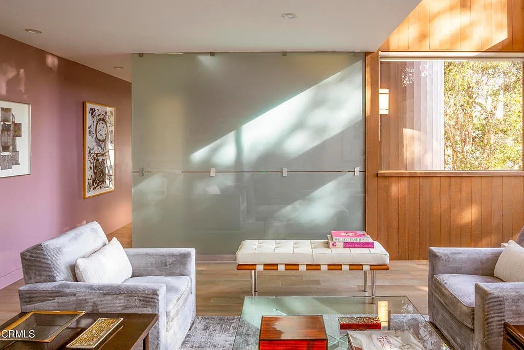 A sleek glass panel wall and warm wood accents set the stage for a retro-futuristic design. Streamlined furniture and ample natural light create a perfect balance of vintage charm and space-age sophistication.