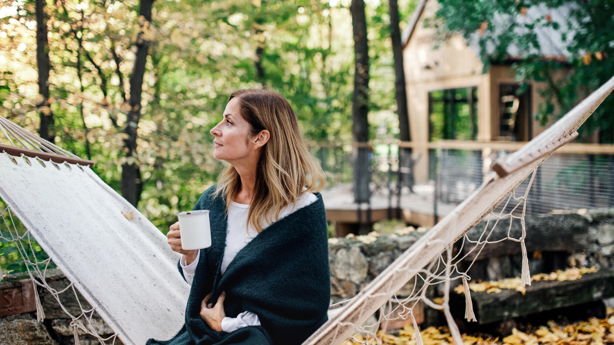 Woman standing outside a tiny home, drinking coffee.