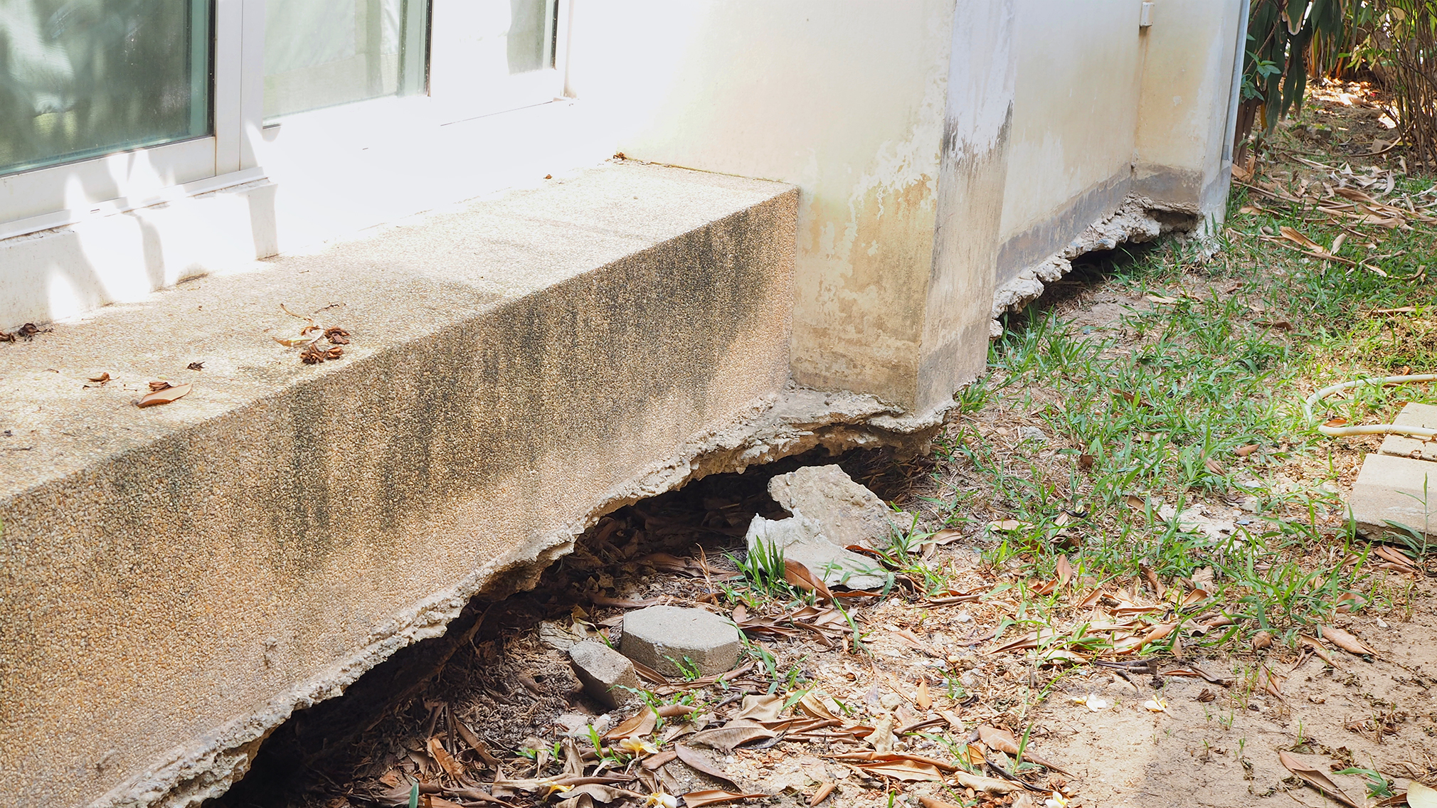 Photo shows a concrete foundation with eroded soil beneath it, and some disintegration of the concrete
