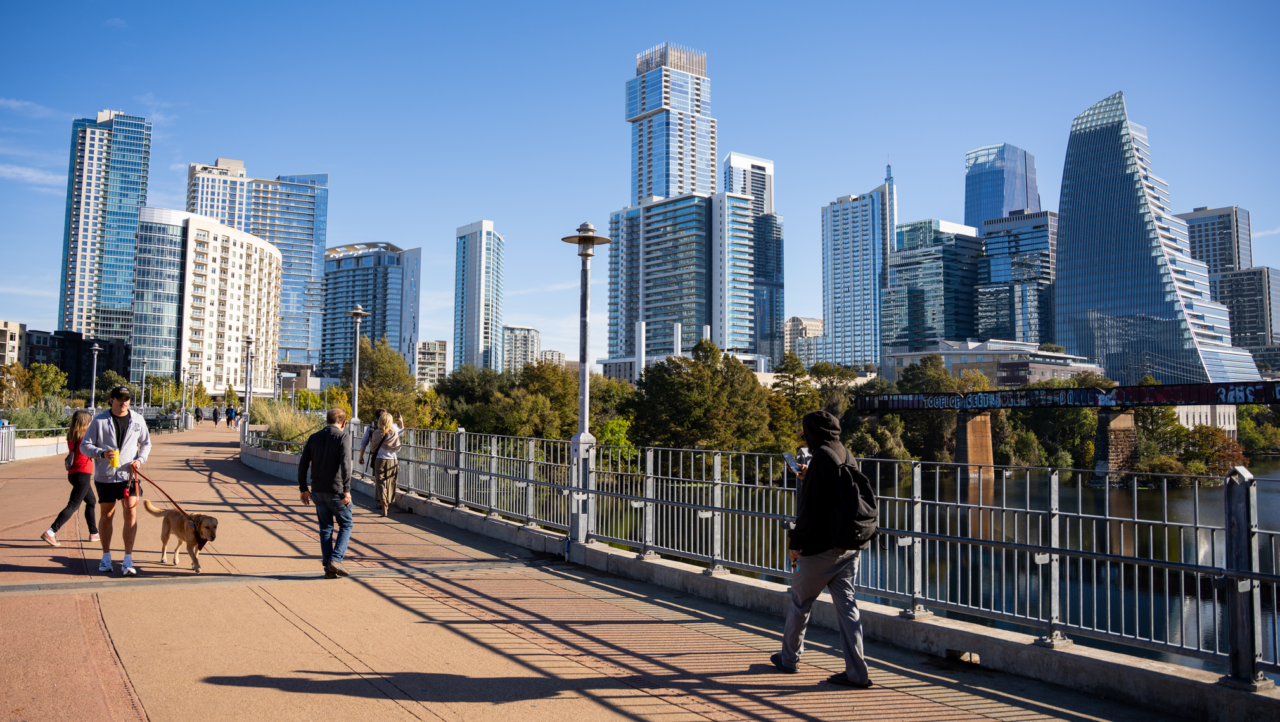 A bridge overlooking the high-rises of downtown Austin, with pedestrians passing by.