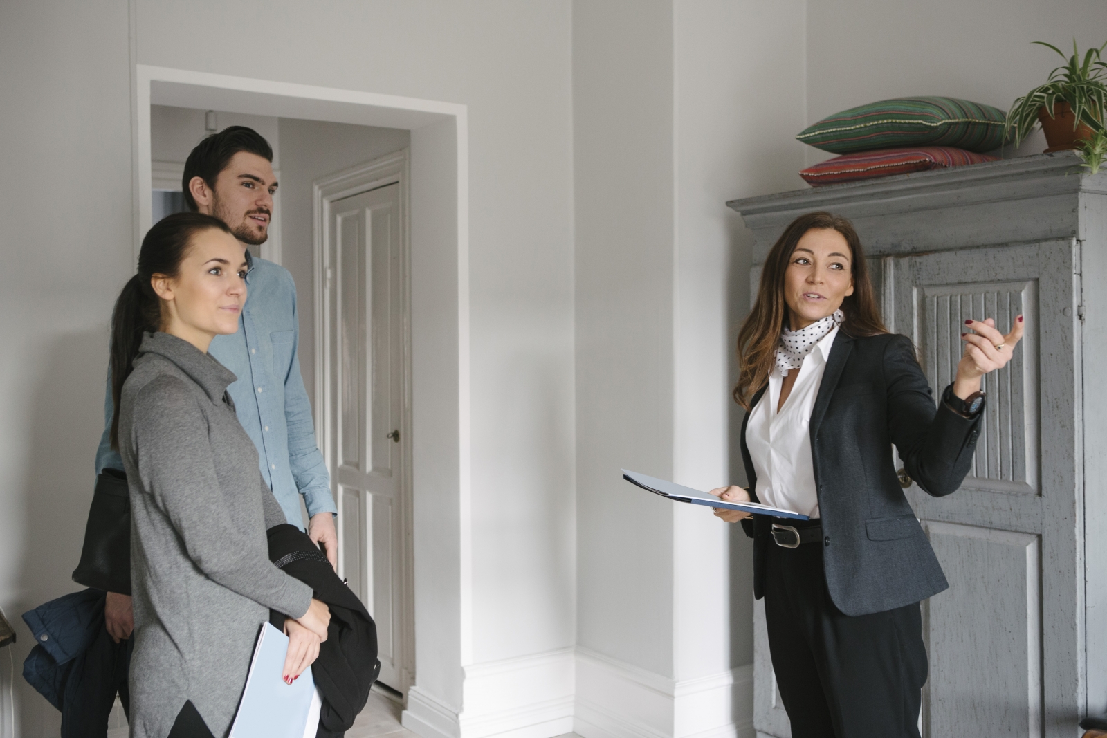 On-site sales agent shows young couple multifamily apartment