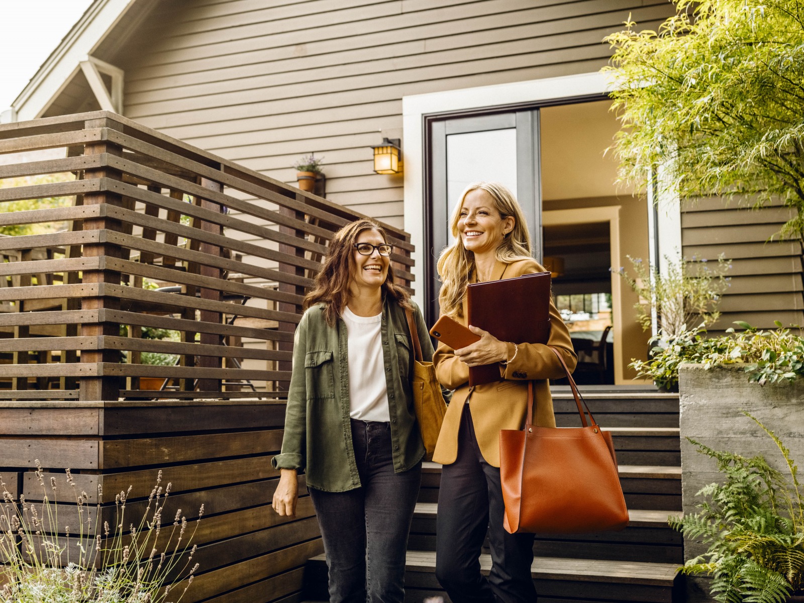 An agent and her client exit the rear door of a house.