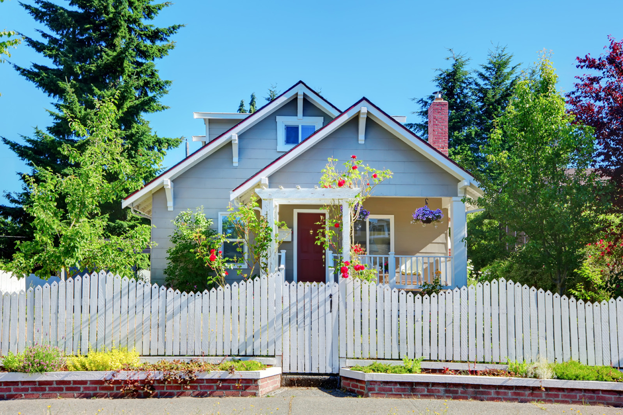 Cute small grey old craftsman style house with white fence