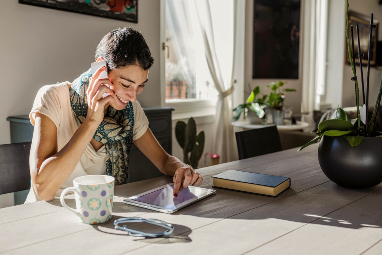 Woman looking at tablet while on phone