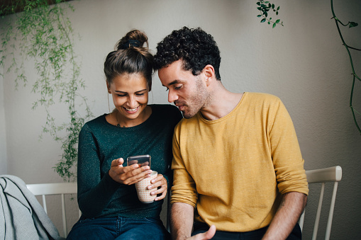 Woman and man smiling and looking at a phone