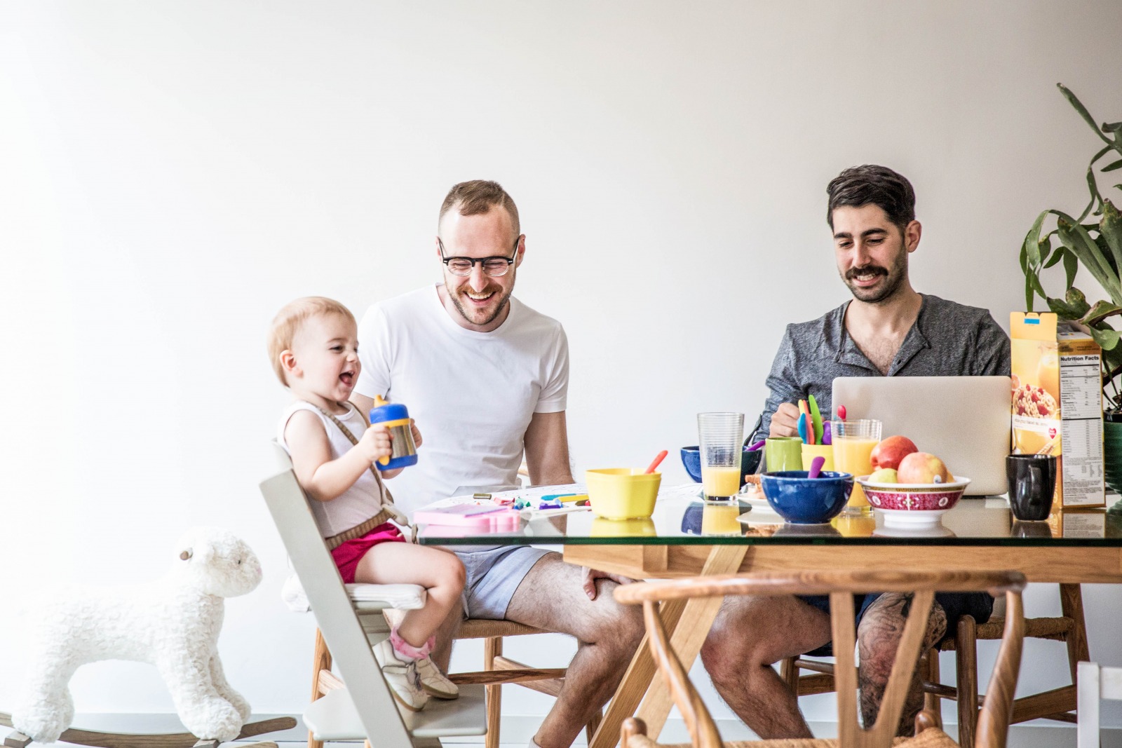 Two men and their toddler child having breakfast