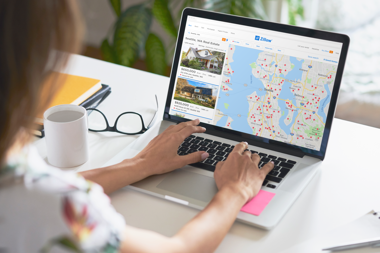 Woman looking at laptop screen of a Zillow search results screen with map