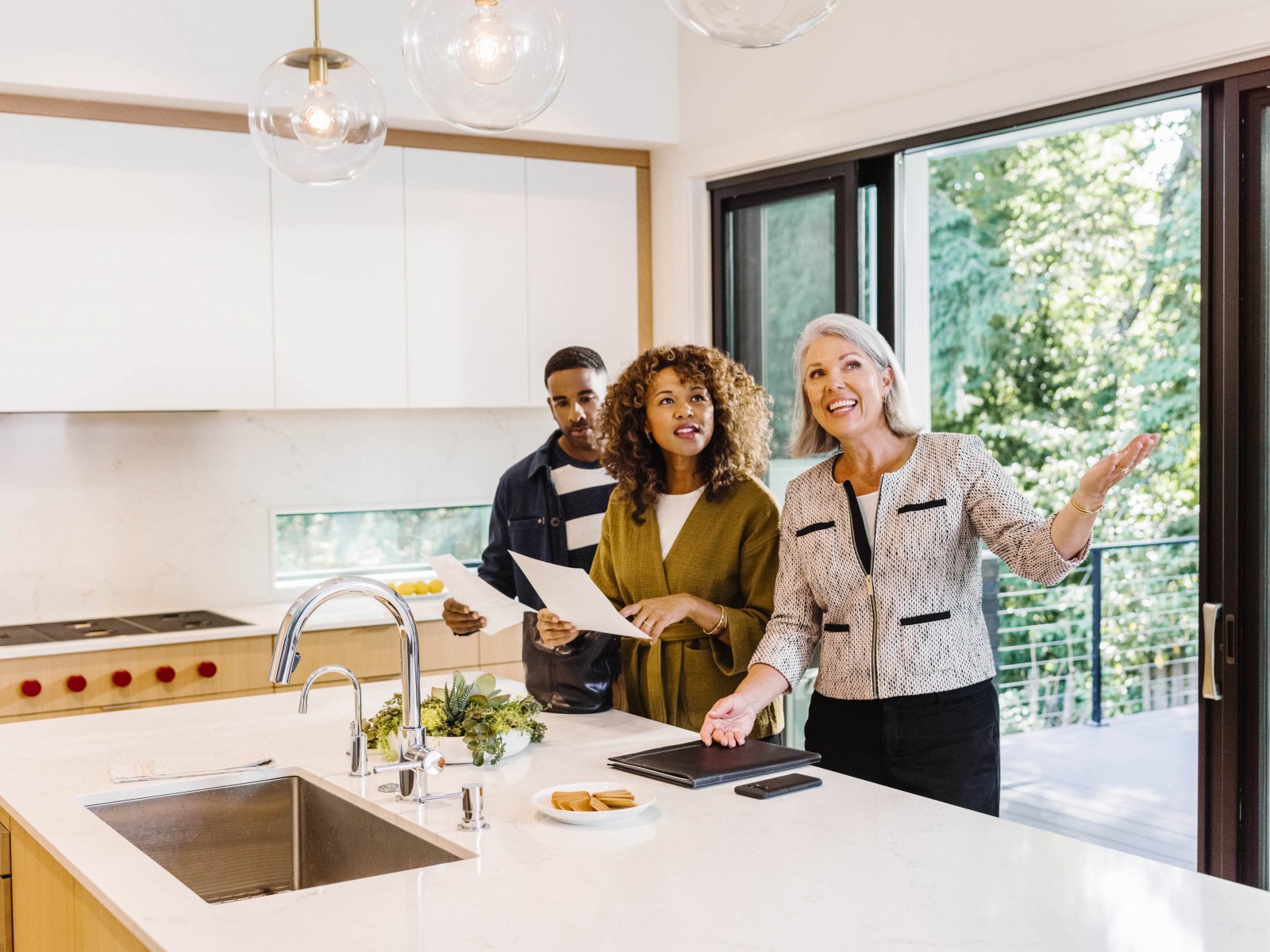 An agent shows two home shoppers the kitchen of a home.