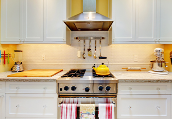 Home kitchen stovetop with white cabinets and granite counter tops.