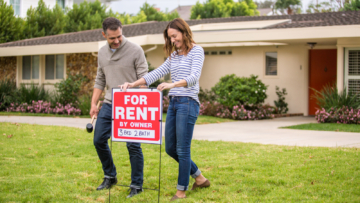 couple adding a for rent sign in their front yard