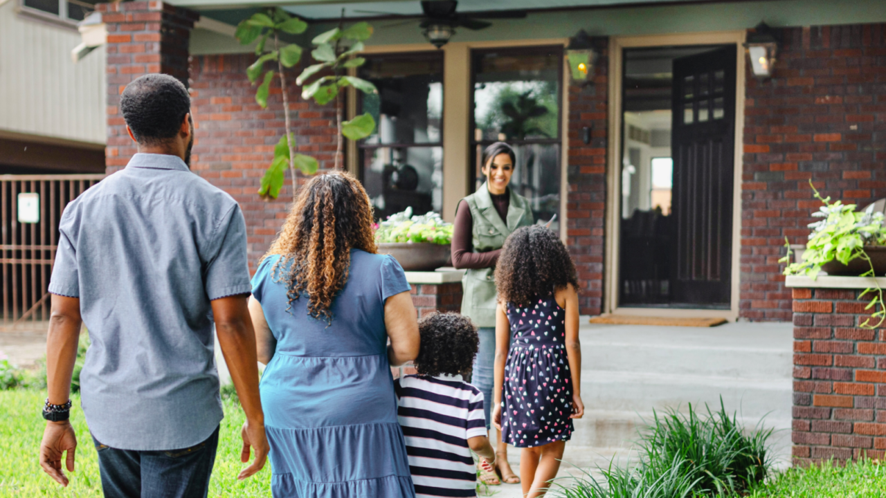 family walking towards house and real estate agent