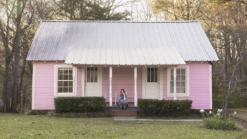 kacey musgraves sitting on the patio of her pink childhood home