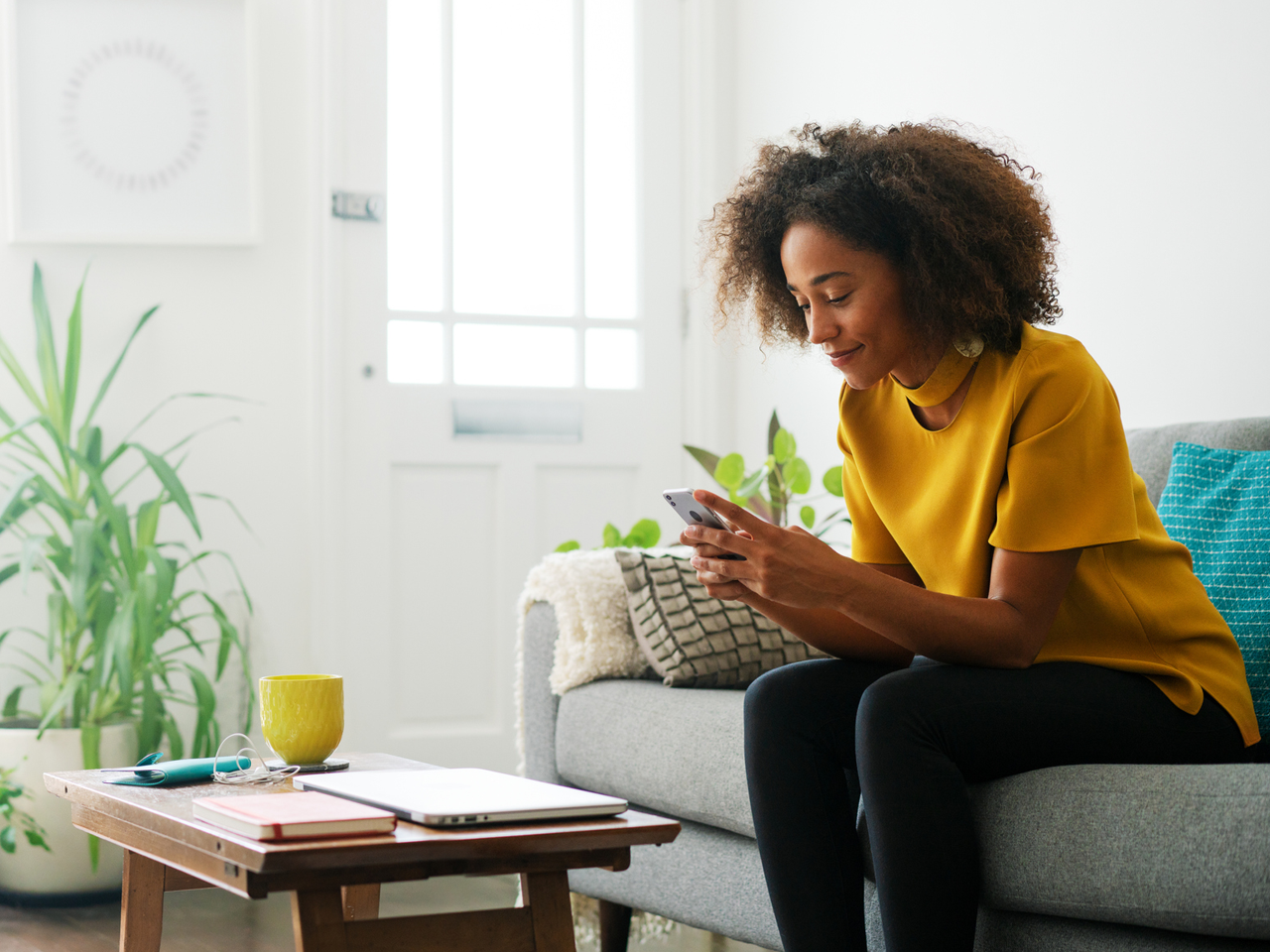 woman sitting on a couch looking at her mobile phone