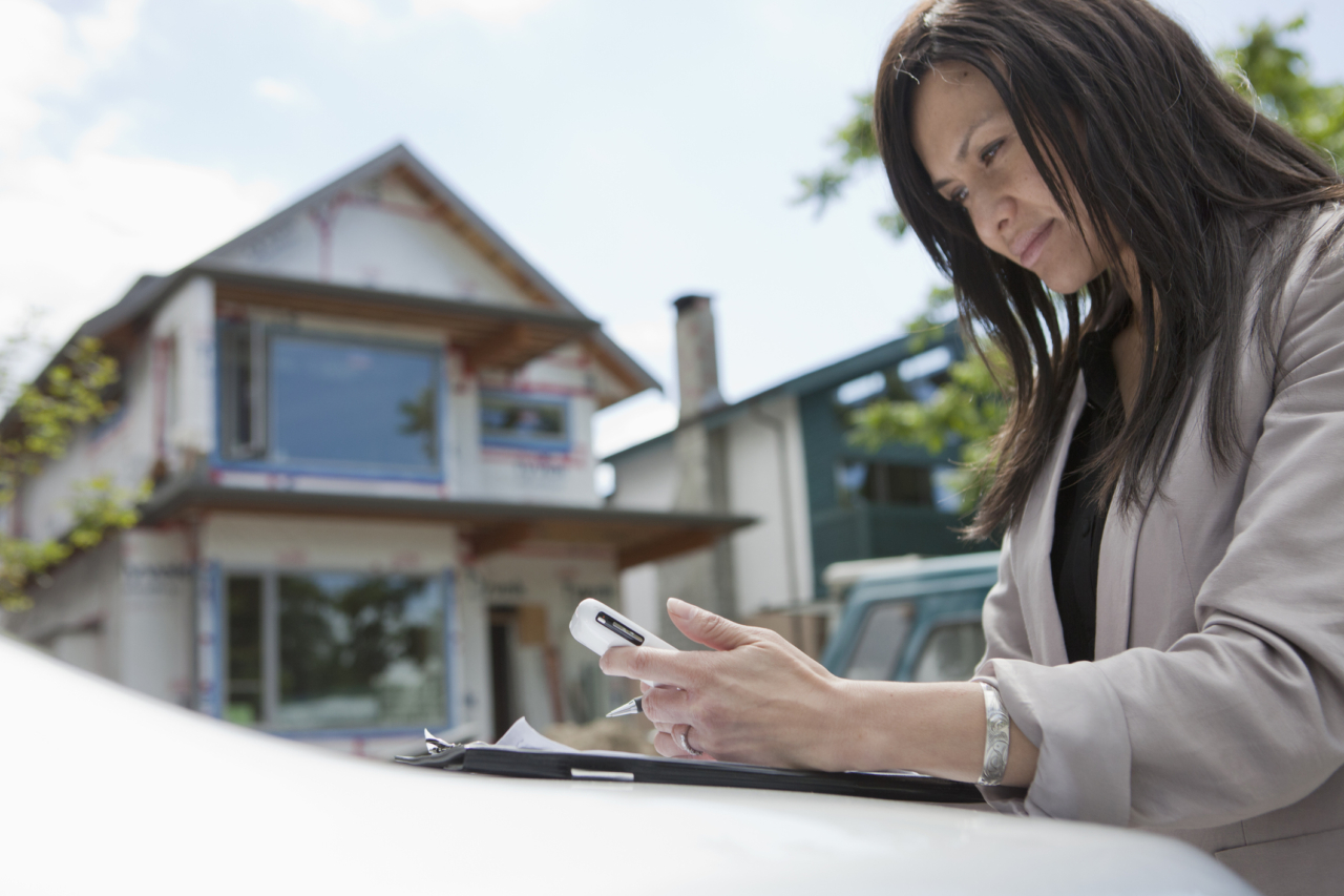 real estate agent texting on phone outside of home