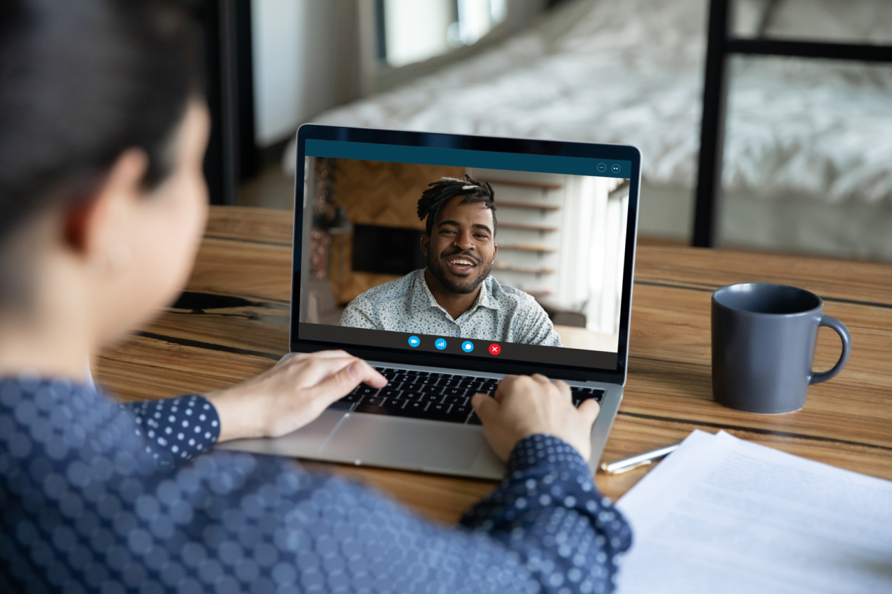 over-the-shoulder-angle of consultant talking with man through the computer